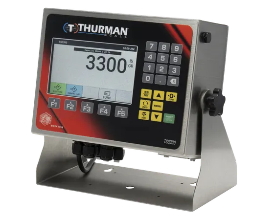 TS3302 analog scale indicator in a NEMA 4X stainless steel washdown housing on a desk and wall stand, 7-inch color display and numeric keypad.