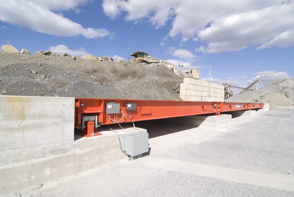Diamondback 8560XD from its approach wall at a quarry, on an above-ground foundation with daylight under the weighbridge