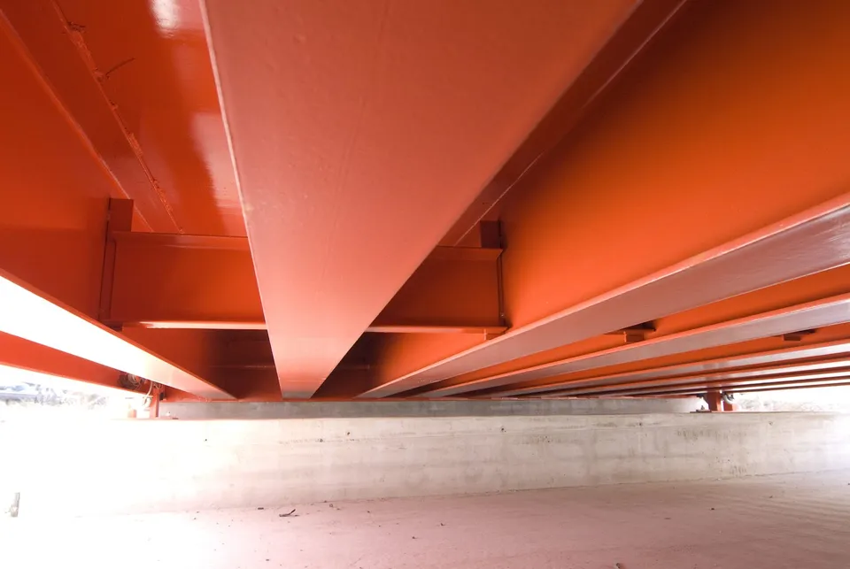 Underside of a Diamondback 8560XD weighbridge: orange structural I-beams over the concrete foundation