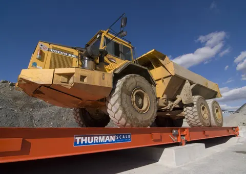 Thurman Diamondback 8560XD steel deck truck scale in orange with an articulated off-road haul truck on the deck at a quarry
