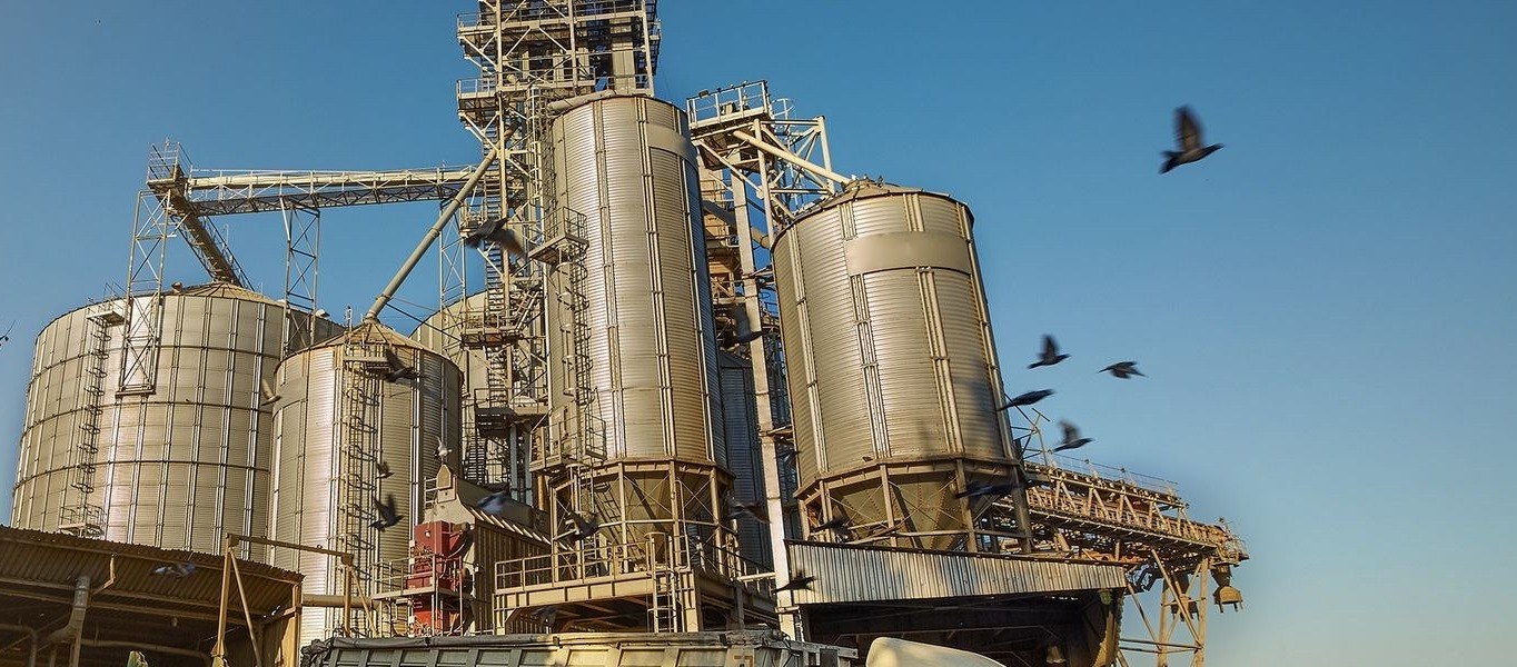 Grain terminal silos and elevator legs with a loaded grain trailer pulled up to the receiving pit