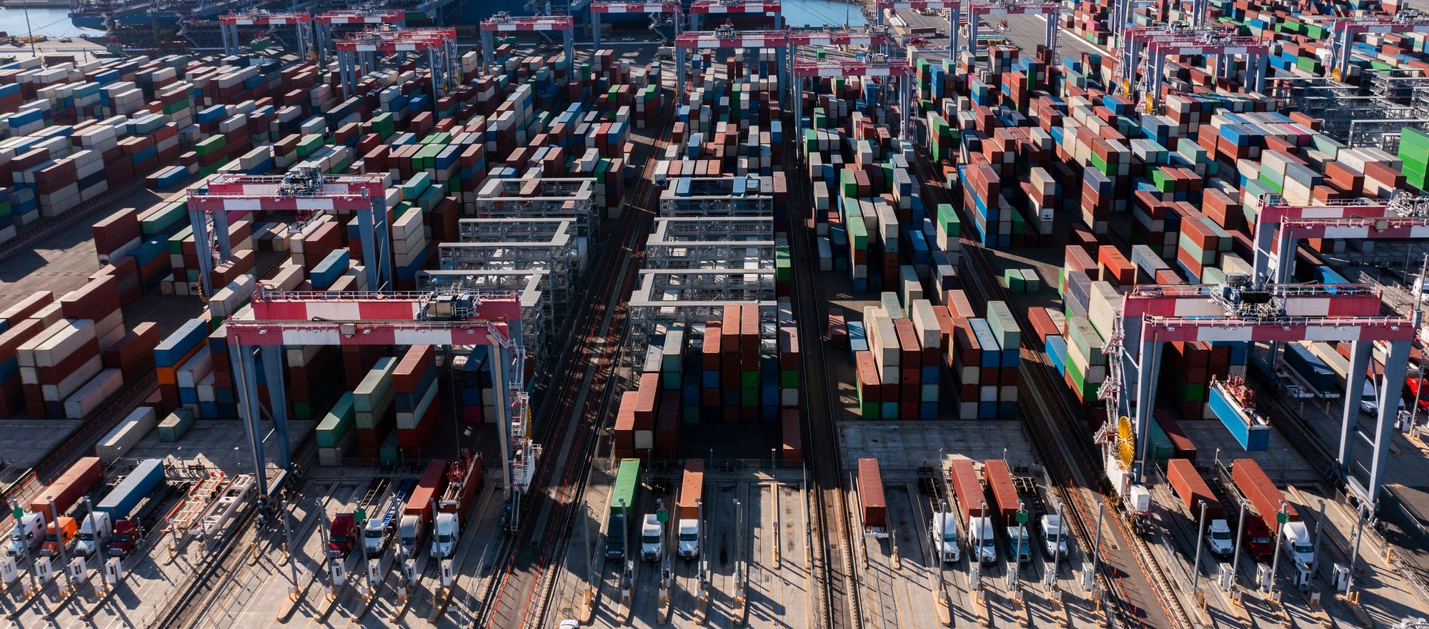 Aerial view of an intermodal container terminal: stacked containers, gantry cranes and trucks in the loading lanes